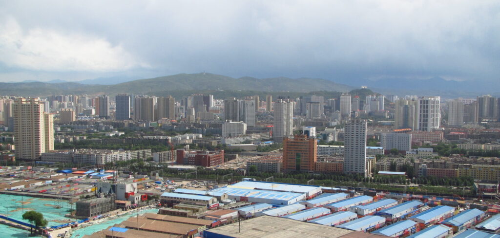 Xining's skyline filling a highland valley beneath dry hills and storm clouds