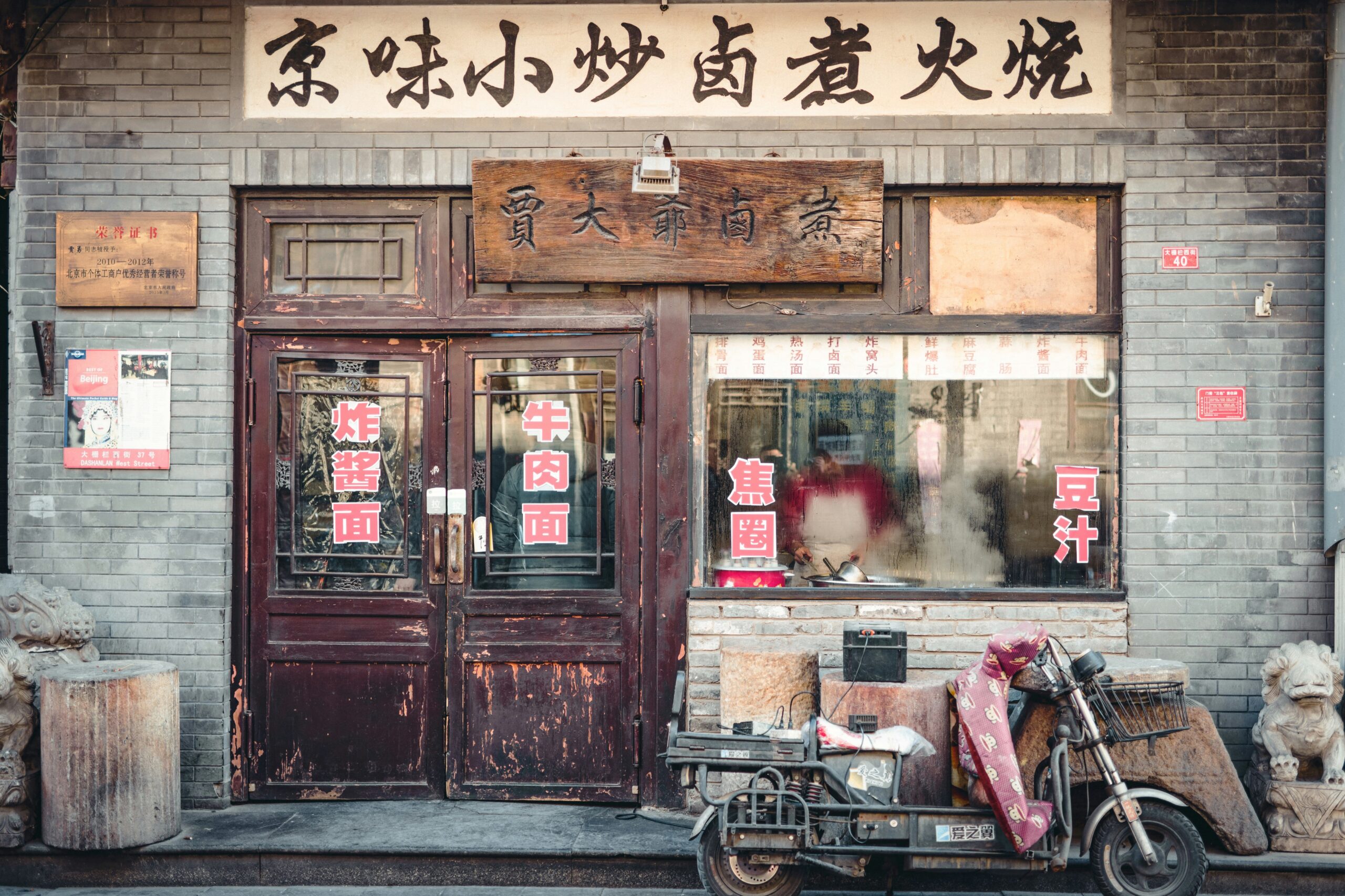 Traditional Beijing snack shopfront with Chinese signs and a parked scooter