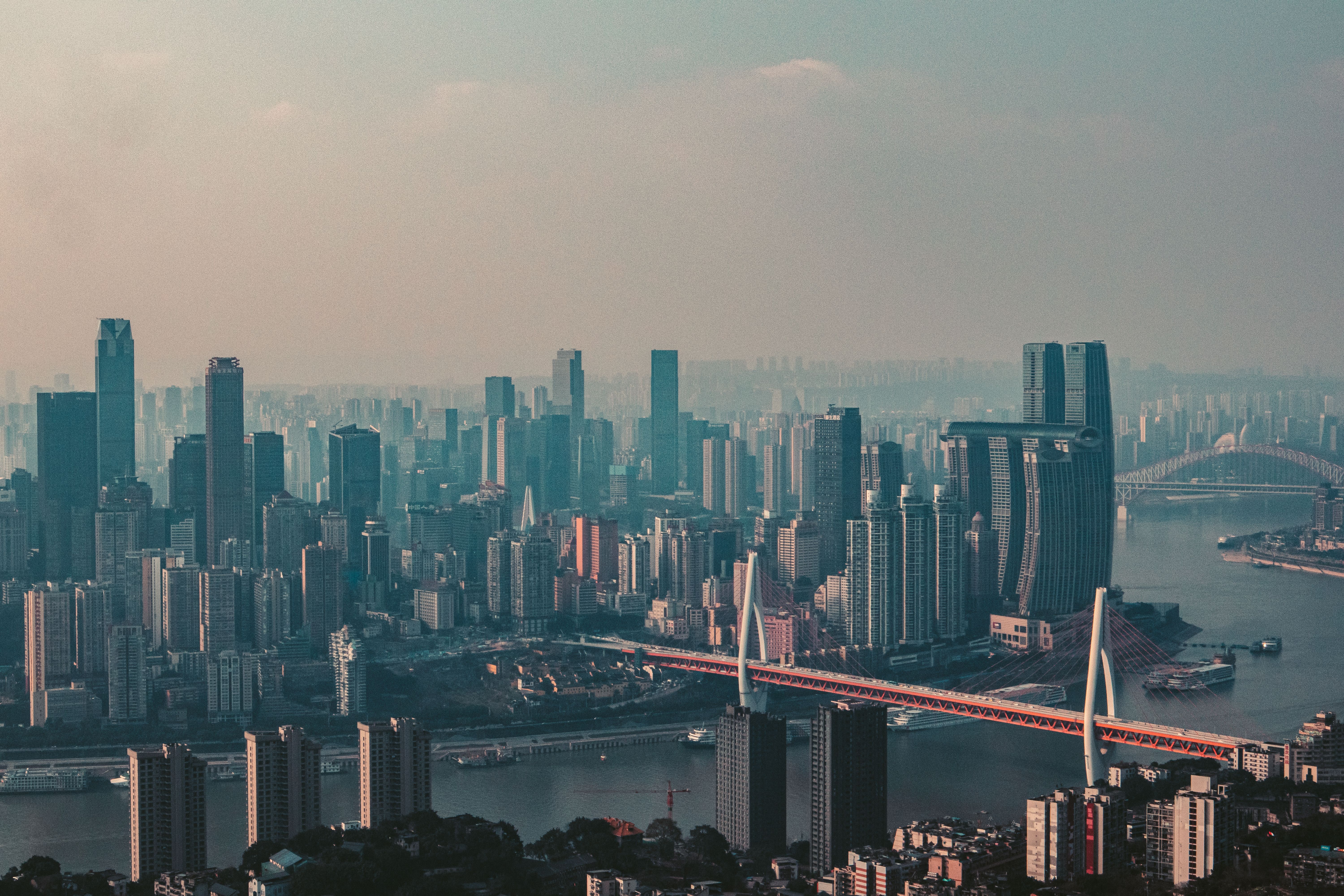 Wide hazy view of Chongqing's river, bridges, dense skyline and surrounding mountains