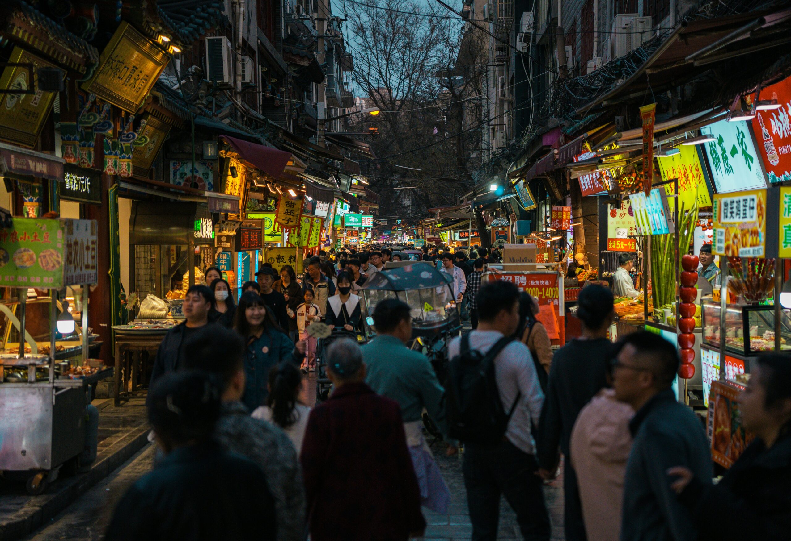 Busy traditional food street with stalls, signs and pedestrians