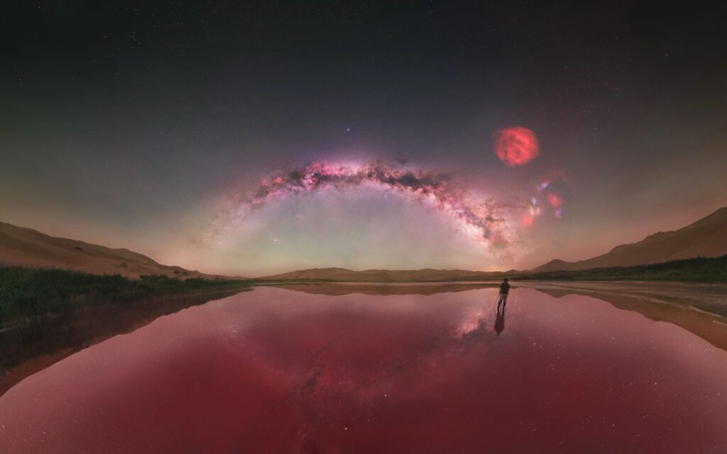 Night view of a desert lake and sand dunes beneath the Milky Way in Badain Jaran Desert, China
