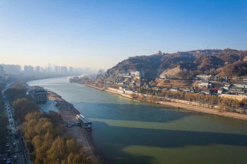 Riverfront cityscape with a hillside pavilion and winter trees