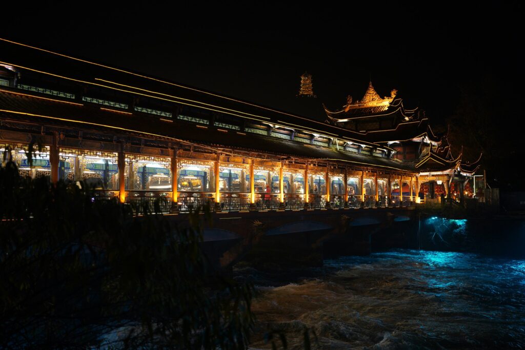 Illuminated traditional buildings beside the river at night in Dujiangyan, Sichuan