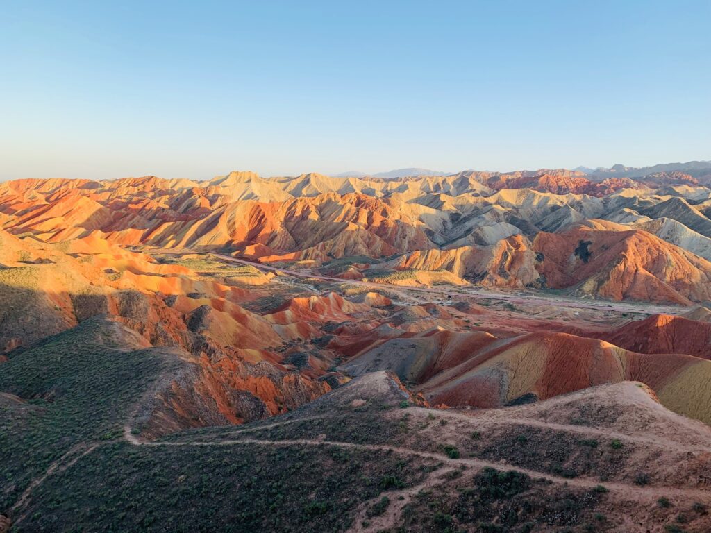 Layered red, ochre and pale hills beneath a clear blue sky
